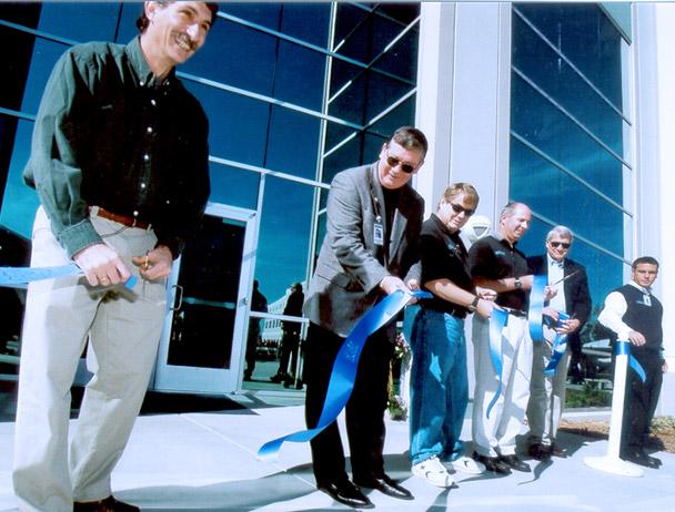 Mark Dankberg and five Viasat employees cutting a blue ribbon in front of the new Carlsbad, CA campus